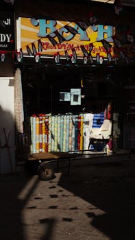 Vibrant fabric rolls on display outside a Dubai textile shop bathed in sunlight.
