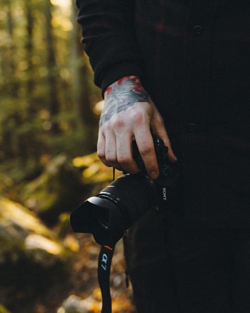 Hand of Unrecognizable Man Holding Photo Camera with Forest in Background