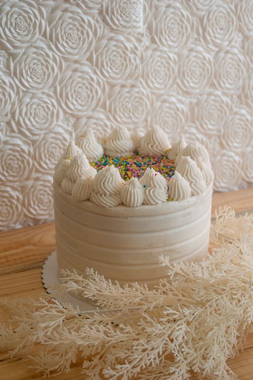 Free Delight in a white frosted cake topped with colorful sprinkles, presented on a wooden surface. Stock Photo