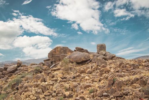 Free A rugged rocky terrain under a bright blue sky with scattered clouds. Stock Photo