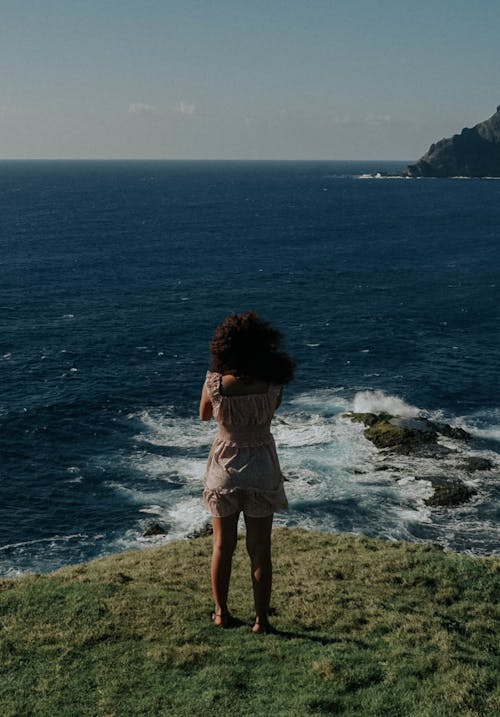 Woman Standing on Mountain Top Beside the Sea