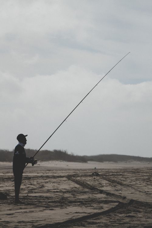 Free A fisherman silhouetted against the sky, casting his line on Altata Beach, Mexico. Stock Photo