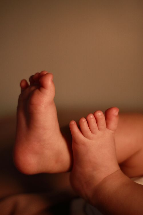 Free A close-up shot of an infant's adorable feet against a warm background. Stock Photo