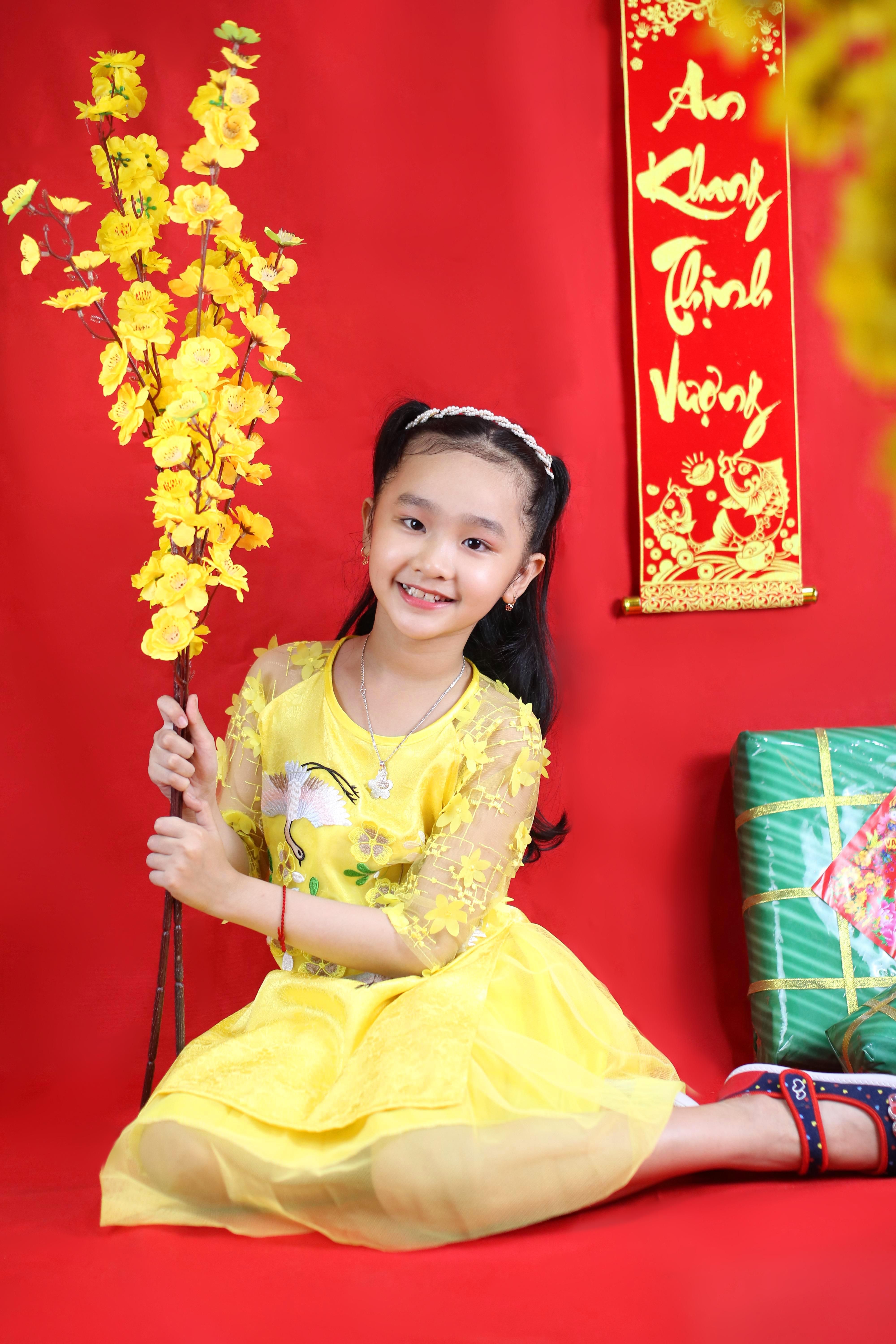 Smiling girl in yellow dress holding flowers on Lunar New Year.
