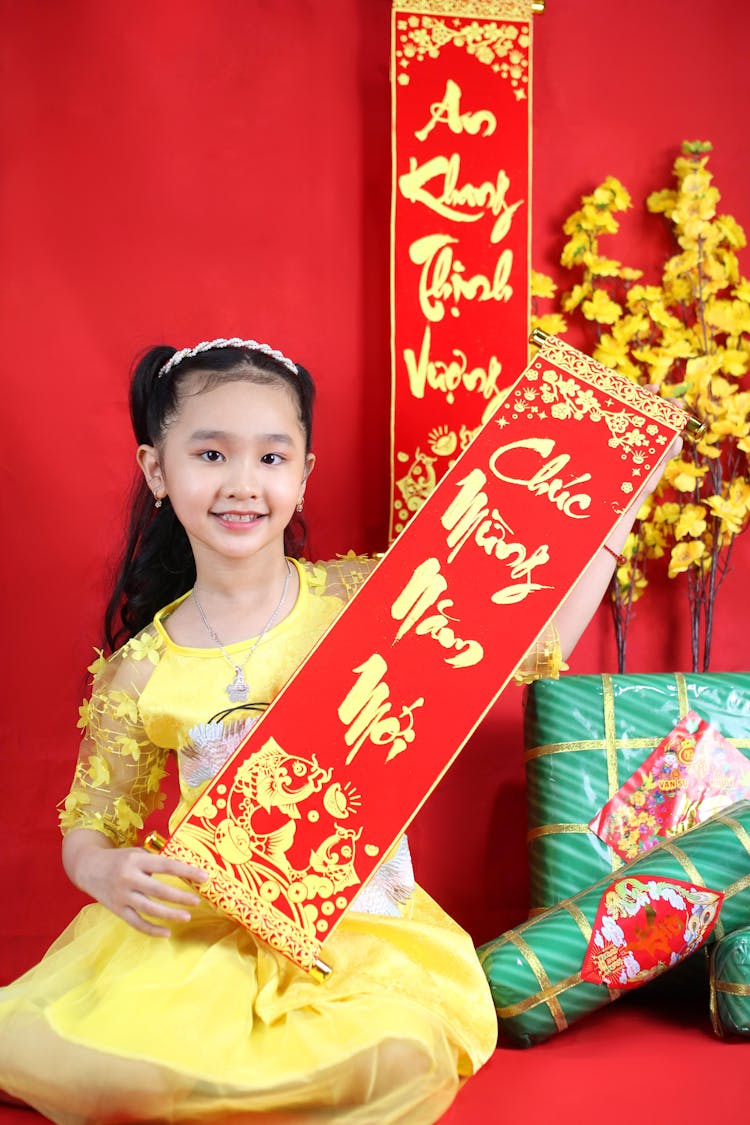 A Woman In Yellow Dress Holding A Red Banner