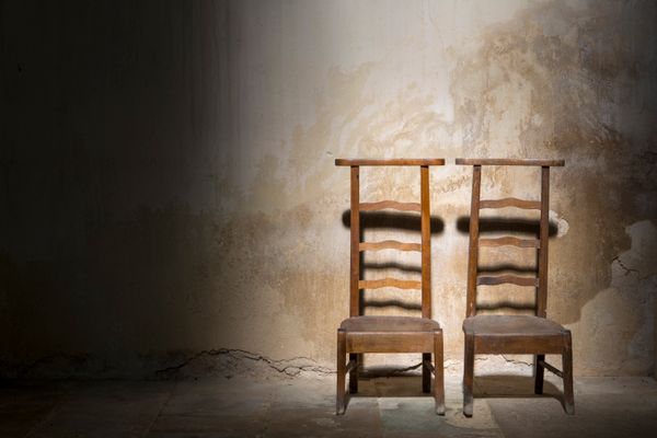 Two wooden chairs against a worn wall in an empty room — photo by Jan van der Wolf on Pexels