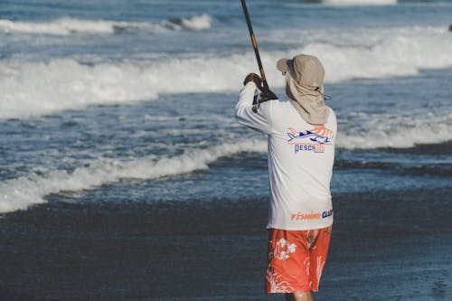 Free Person Holding Fishing Rod on Beach Stock Photo