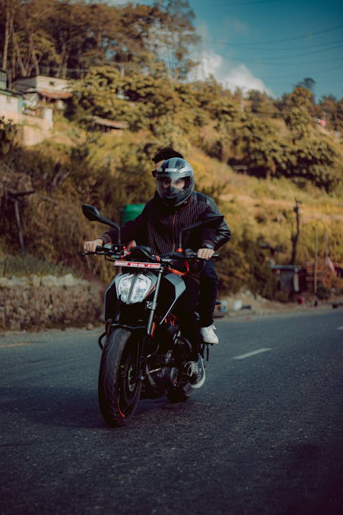 Photo of a Man with a Black Helmet Riding a Motorcycle