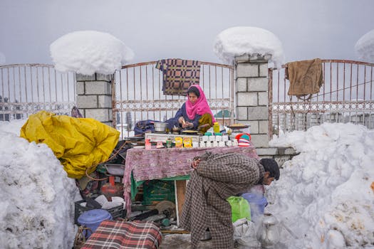 A vibrant tea stall setup amidst a snowy urban environment, with two adults attending the stall.