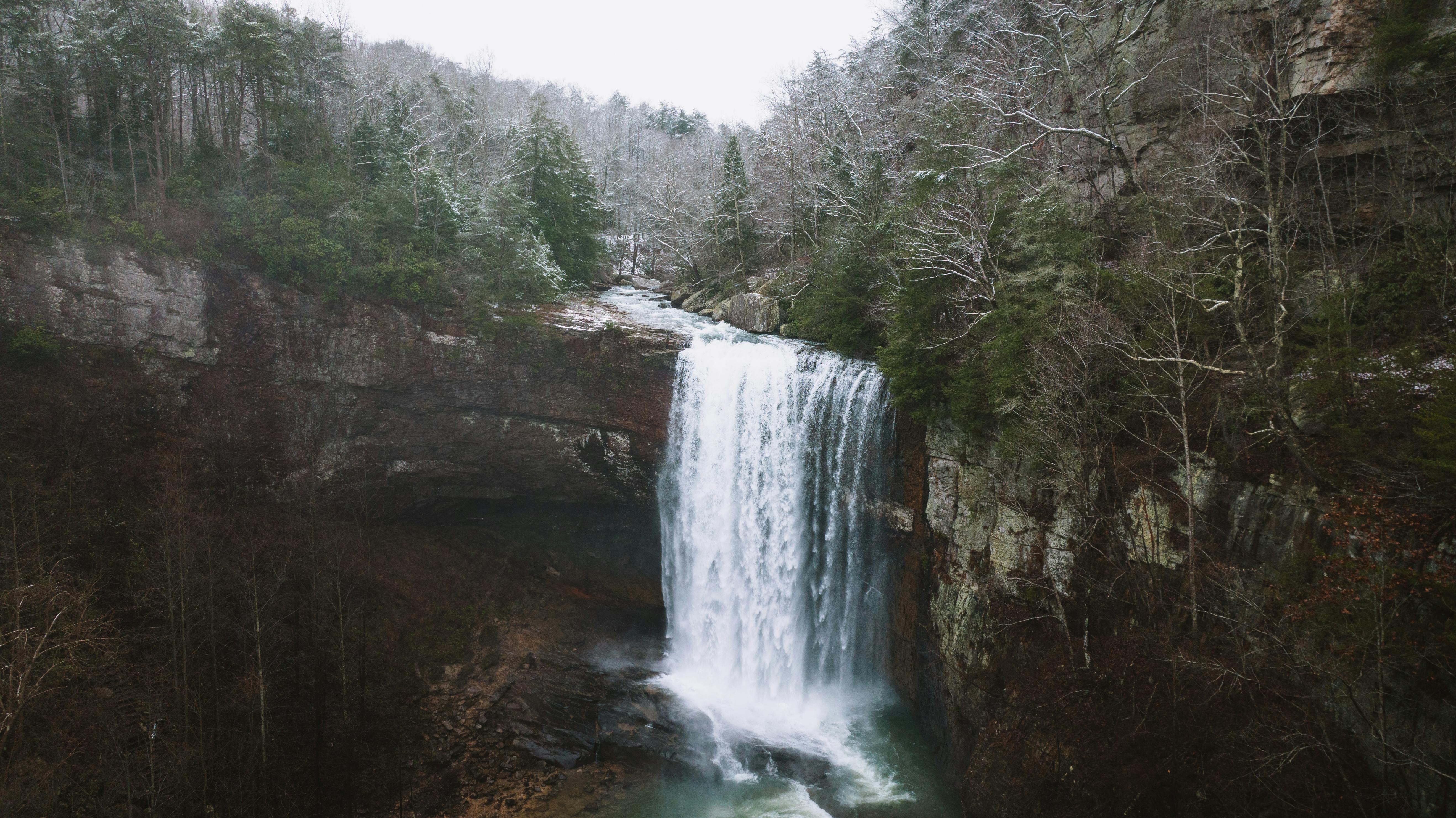 Captivating winter waterfall in Chattanooga Valley, surrounded by cliffs and evergreen forests.