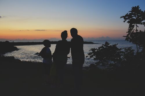 Free A serene silhouette of a family by the beach during sunset, capturing a peaceful moment. Stock Photo