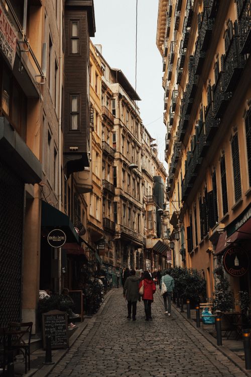 Free A picturesque European street scene with people walking down a historic cobblestone path between buildings. Stock Photo