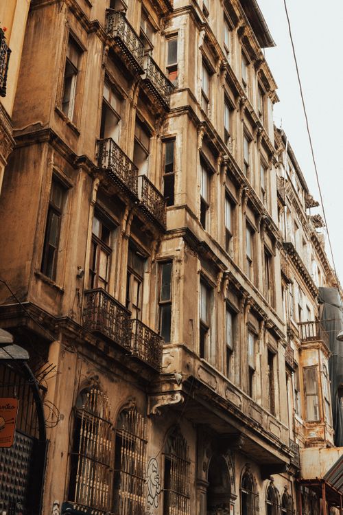 Free Aged European building with ornate balconies and a vintage facade, captured from a street view. Stock Photo