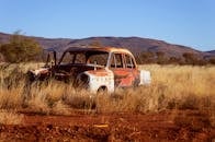 在干燥的沙漠景观中，老式汽车在群山背景下腐烂