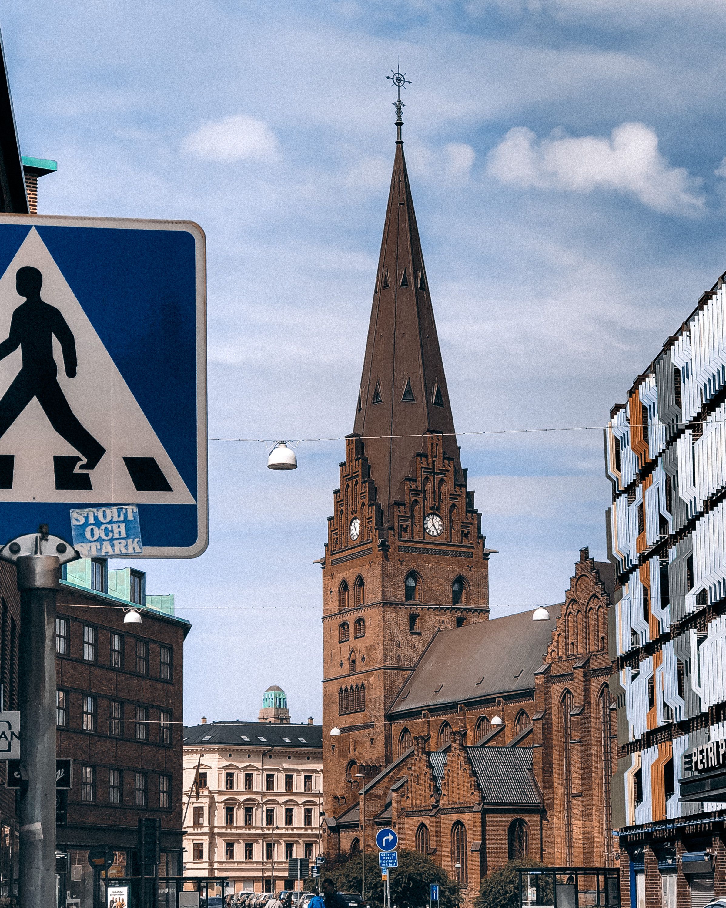 Urban scene of St. Peter's Church in Malmö, Sweden featuring a prominent pedestrian sign in the foreground.
