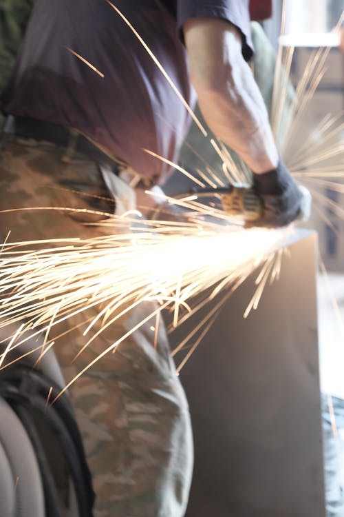 Person Wearing Gloves Near Sparking Metal Tool