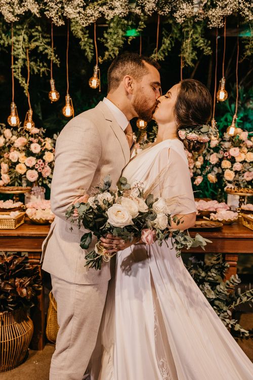 Free Couple kissing at their wedding reception surrounded by flowers and lights. Stock Photo