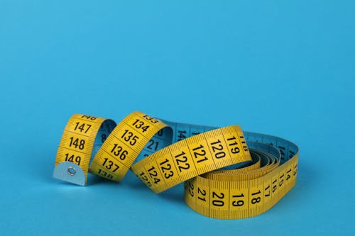 Free Yellow Tape Measure on Blue Background Stock Photo