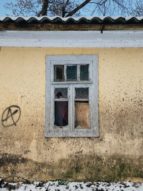 Free An old, abandoned building with a broken window and graffiti on a yellow wall. Stock Photo