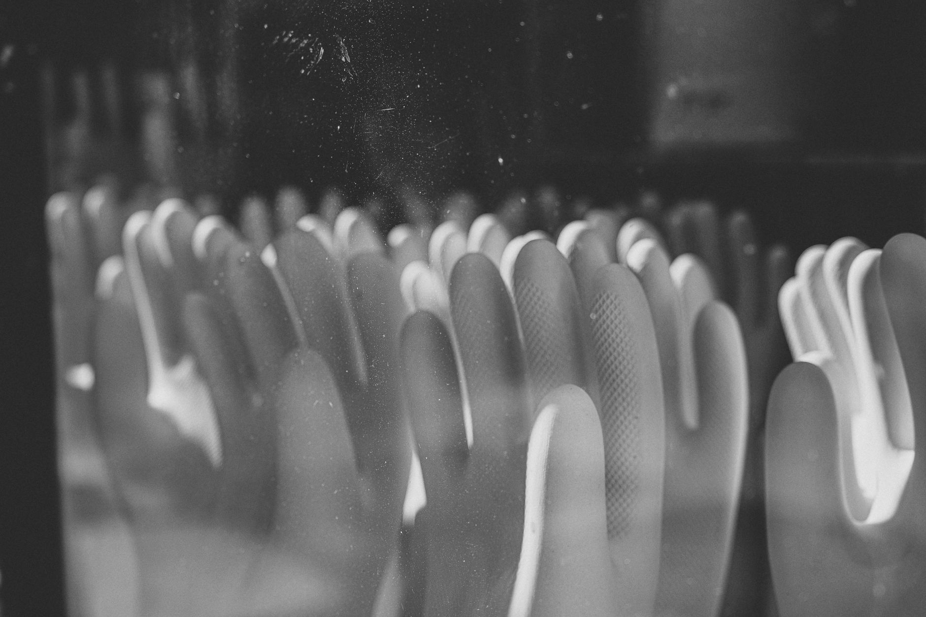 Monochrome photo featuring multiple rows of gloves in a close-up view.