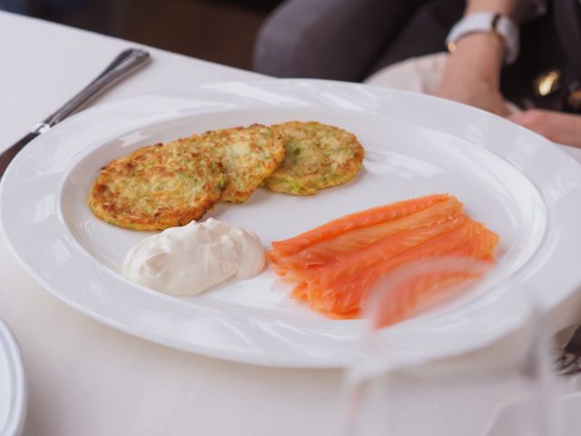 Delicious salmon slices with crispy potato pancakes and creamy sauce on a white plate.