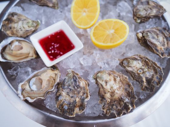Raw oysters on crushed ice with lemon halves and a dish of red mignonette