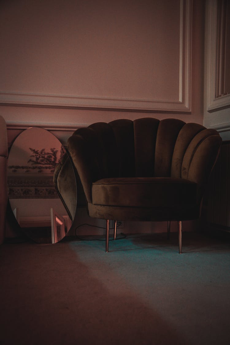 Brown Velvet Chair Near An Oval Mirror