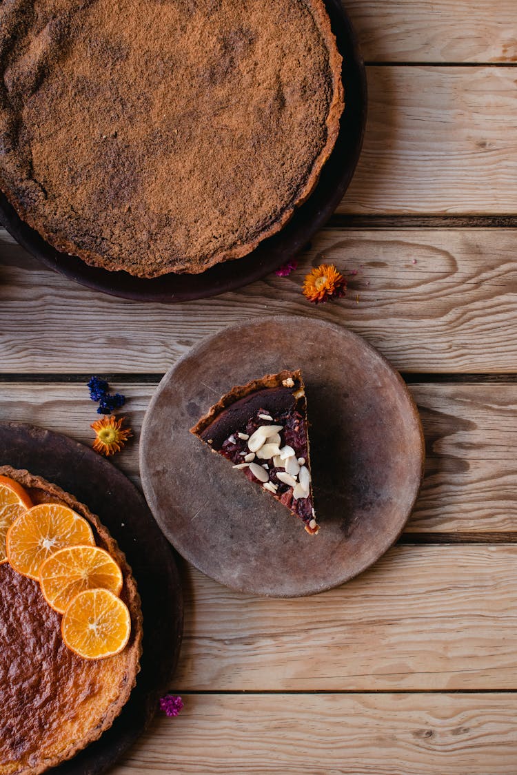 Sliced Cake On A Brown Plate Near Cakes On A Wooden Surface