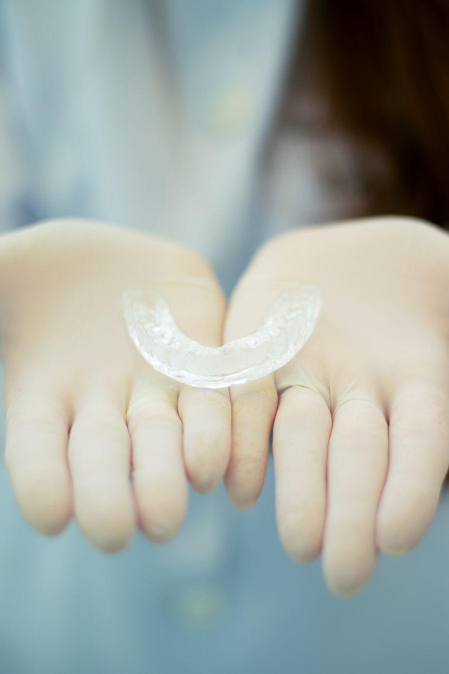 A clear aligner tray held in two hands