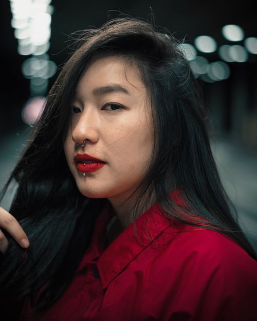 Free Captivating portrait of a woman with red lips and dark hair, set against a blurred bokeh background. Stock Photo