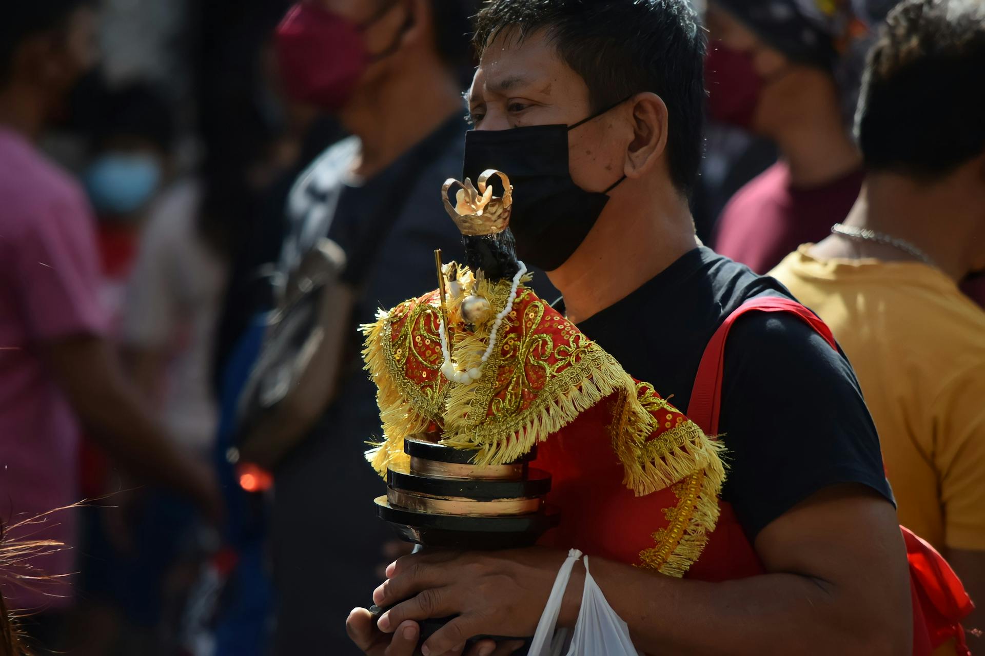 A man participates in the vibrant Sinulog Festival parade in Cebu City, Philippines, holding a Santo Niño statue.