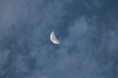 Free A serene half moon peeks through a cloudy night sky, showcasing nature's beauty. Stock Photo