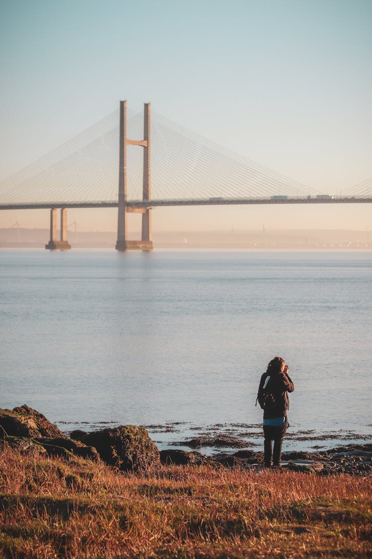 Woman Standing On Shore Of Strait In Front Of Golden Gate Bridge, San Francisco, USA