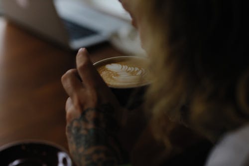 Free Person with Arm Tattoo Drinking Cappuccino Stock Photo
