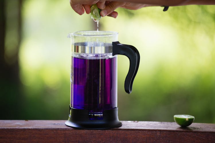 Purple Liquid In A Kettle And Man Squeezing A Lime