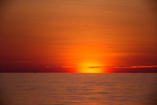 A breathtaking view of a sunset over the ocean, capturing vibrant orange and red hues in the sky.