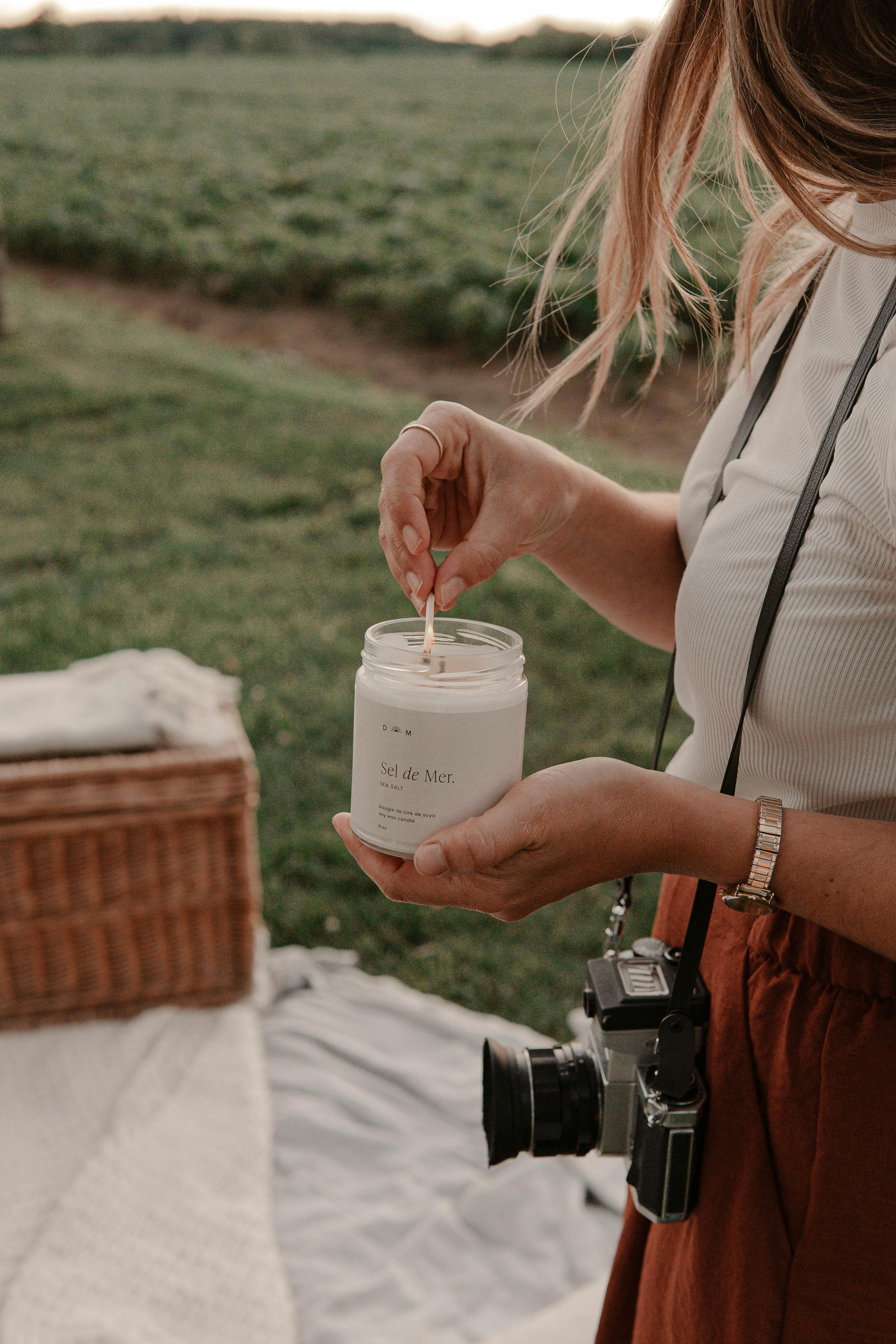 Close-up of a woman lighting a candle at a serene outdoor picnic. Capturing tranquility.