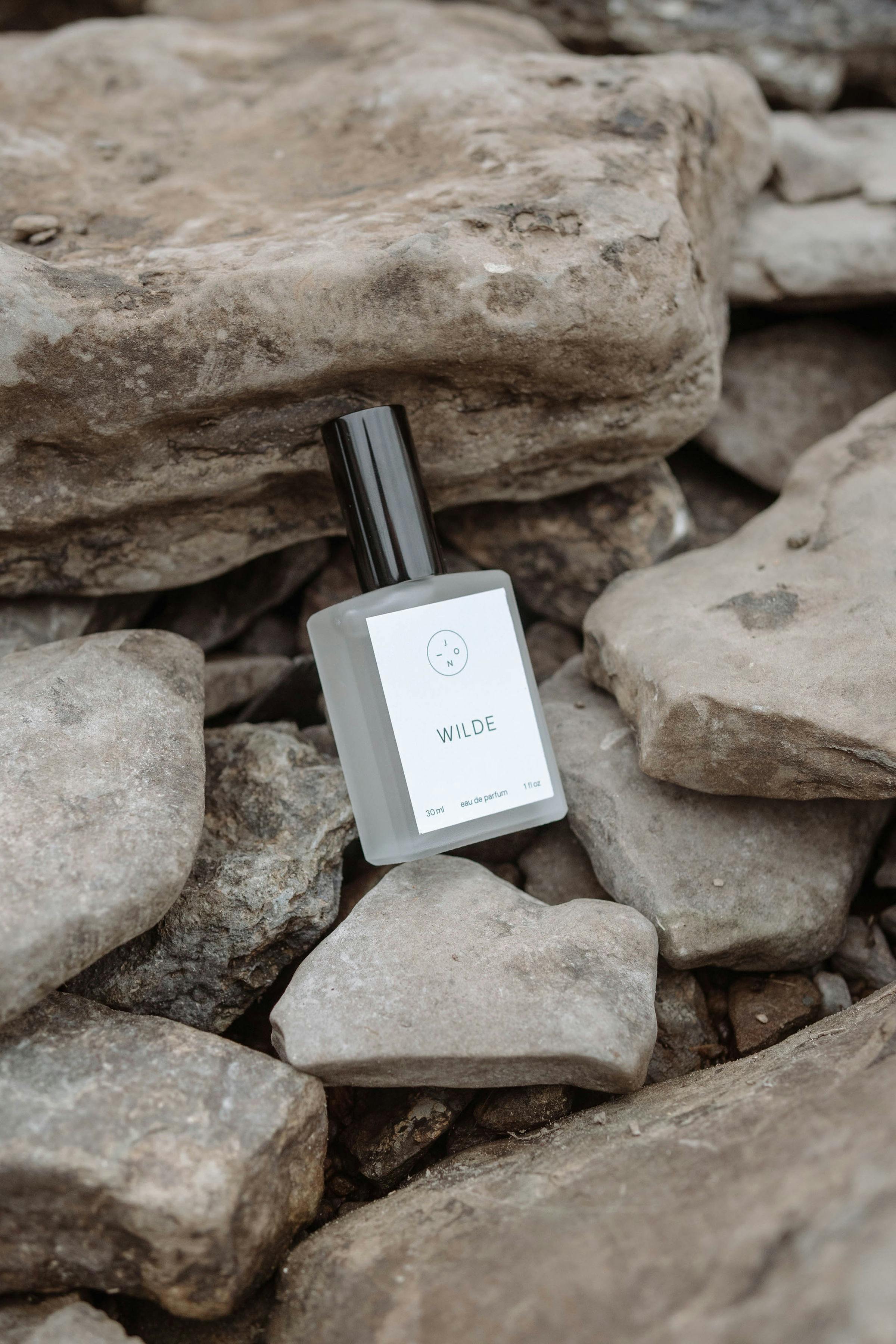 Stylish perfume bottle set on rugged rocks, evokes natural elegance and earthy tones.
