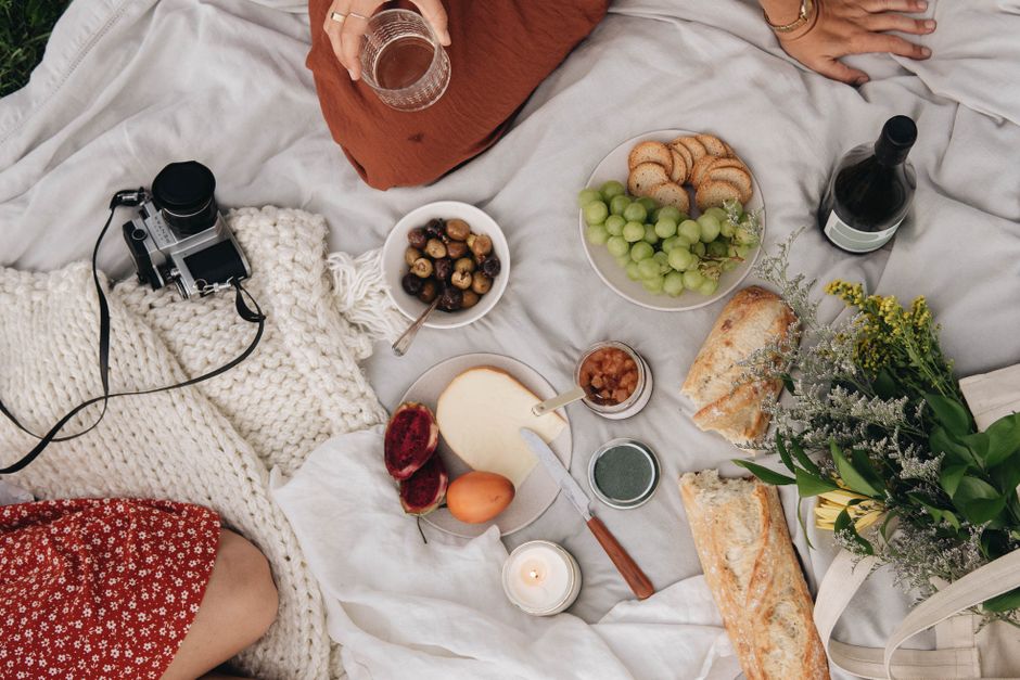 Top view of a cozy picnic with wine, cheese, bread, grapes, and a retro camera.