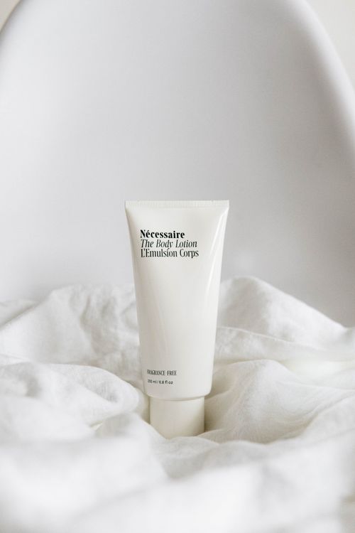 Close-up of a body lotion bottle on white fabric, representing a lactic acid moisturizer