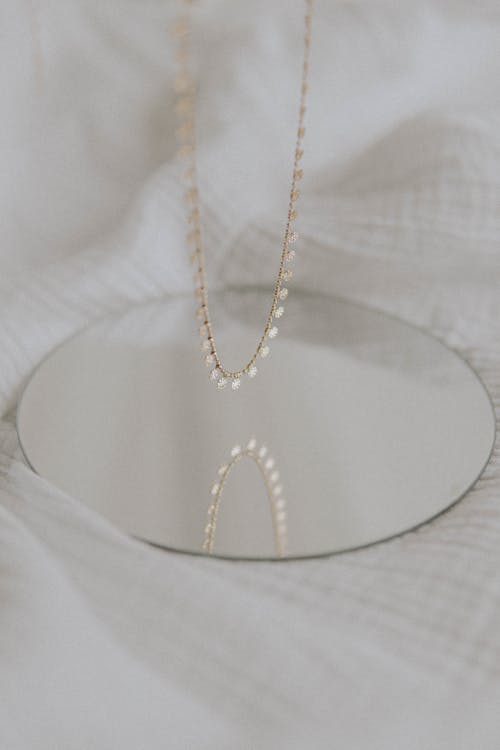 Gold Necklace Near the Round Mirror 