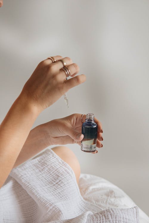 Close-up View of Hands Holding Glass Bottle and Pipette