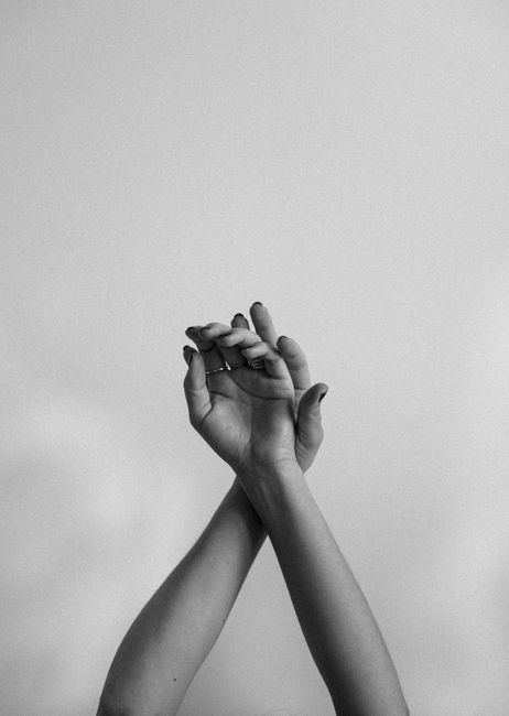 Black and white image showing a close-up of hands raised in an artistic gesture against a gray background.