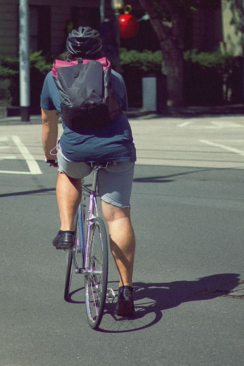Free A cyclist with a backpack rides a bicycle in a city street during the day. Stock Photo