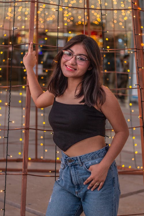 Woman in Black Spaghetti Strap Crop Top and Blue Denim Jeans Smiling