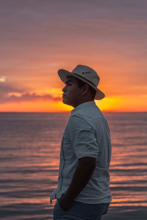 Man Looking Afar while Standing near the Ocean during Golden Hour 