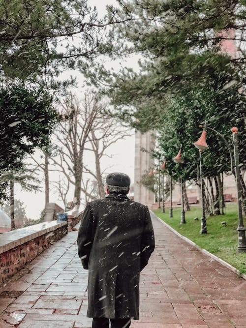 Man Walking on Sidewalk in Snowfall