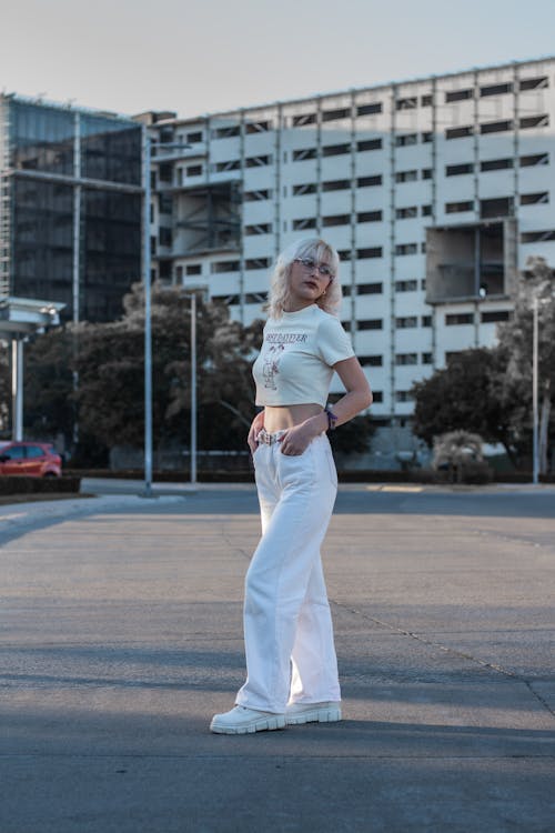 Woman in White T-shirt and White Pants Standing on Concrete Floor