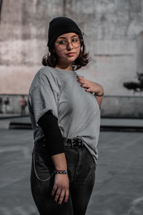 Free Stylish young woman wearing a beanie and gray shirt poses outdoors with a cool demeanor. Stock Photo