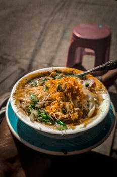 Appetizing bowl of Bangladeshi street food chotpoti with vibrant garnishes.